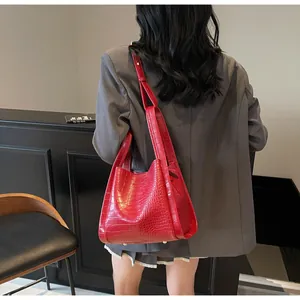 Detail of red crocodile texture tote bag with metallic studs and premium PU leather finish