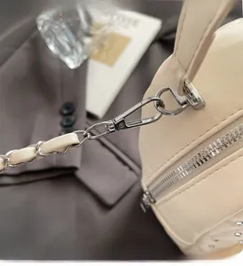 Close-up of beige quilted bag showing silver rivets and metal chain buckle detail