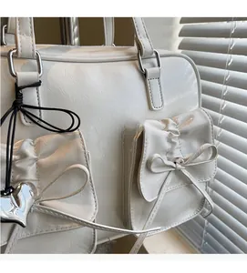 Dettaglio dello zaino bianco stile balletto con tasche a fiocco e ciondolo a cuore
