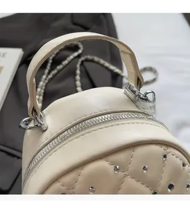 Detail of off-white quilted handbag with silver rivets and metal chain strap
