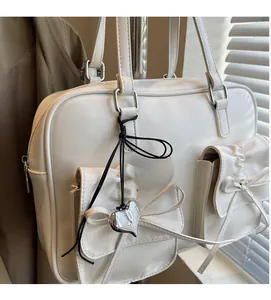 Dettaglio di zaino in pelle bianca con fiocchi decorativi e ciondolo a cuore argento