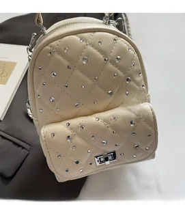 Close-up of quilted cream mini backpack with rhinestones and silver twist lock