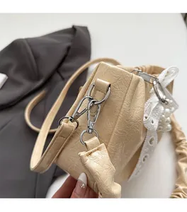 Détail de texture en cuir plissé avec fermoirs métalliques et pendentif en perle
