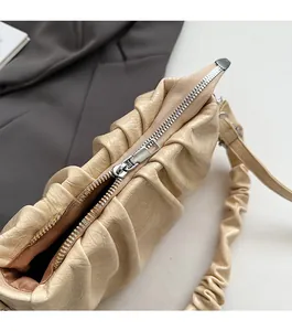 Gros plan du zip fluide et de la texture plissée du sac à bandoulière crème