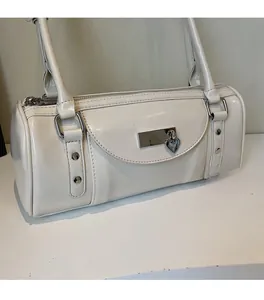 Detail of white bowling bag showing silver heart pendant and metal buckle closure