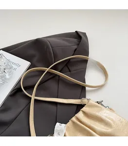 Gros plan du sac en cuir plissé crème montrant la texture douce et la bandoulière
