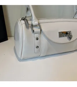 Macro shot of glossy white patent leather bag with silver metal heart charm detail