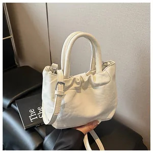Detail view of white ruched bucket bag featuring silver hardware and adjustable strap