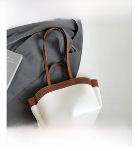 Detail view of two-tone tote bag with side pocket and premium white leather texture