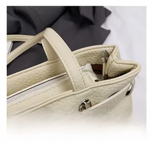 Detail showing high-quality silver hardware and lychee grain texture on a cream shoulder bag