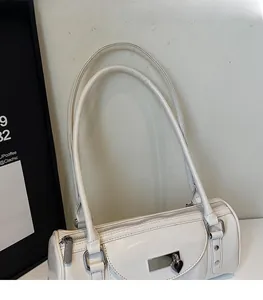 Close-up of white barrel bag featuring a heart padlock pendant and silver hardware detail