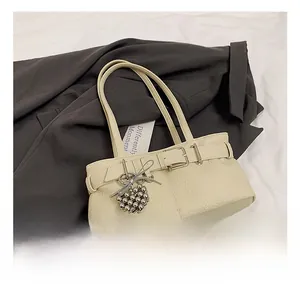 Close-up of beige lychee pattern leather shoulder bag with a silver grape charm detail