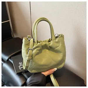 Close-up of pistachio green cloud bag with pleated texture and soft glossy faux leather