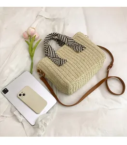 Détails du sac cabas en paille tissée avec anses en cuir marron et foulard déco