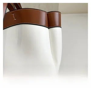 Detail of white leather tote with brown trim and precise contrast stitching texture
