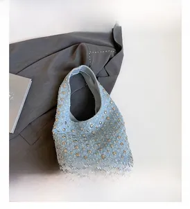 Detail of light blue tweed shoulder bag with metal studs and denim texture on blazer