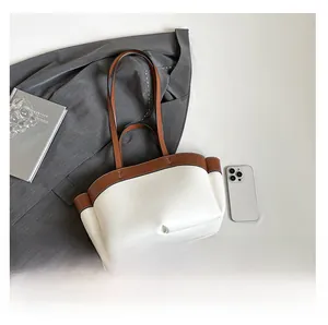 Detail view of large-capacity white tote bag with brown leather handles and side pockets