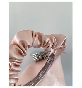 Macro detail of soft light pink pleated handbag handle with fine silver bead trim
