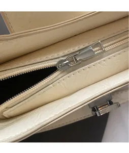 Gros plan sur la fermeture éclair argentée et la texture du cuir crème du sac