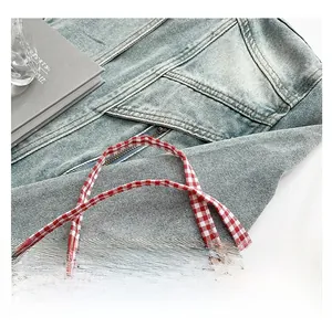 Détail de la sacoche en denim bleu avec bretelles à carreaux rouges et blancs