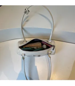 Interior view showing the large capacity of the white cylinder bowling handbag with items