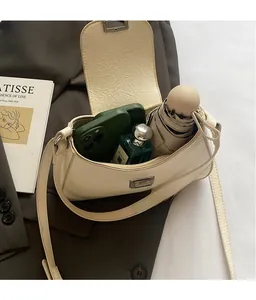 Vue de dessus d'un sac crème montrant l'espace intérieur pour téléphone et parfum