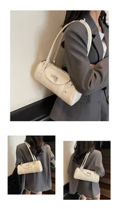 Détail d'un sac à bandoulière cylindrique en cuir beige avec boucle et rivets argentés