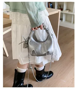 Detail of silver metallic cloud bag with knot handle and chain strap worn on shoulder