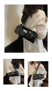 Détail d'un sac bowling en cuir verni noir avec fermoir cœur et doubles anses