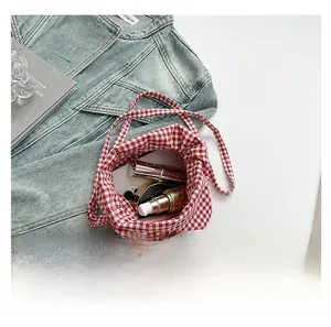 Détail de la capacité intérieure du sac à cordon à carreaux rouges avec cosmétiques