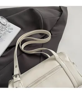 Detail view of adjustable strap with silver hardware on off-white leather pillow bag