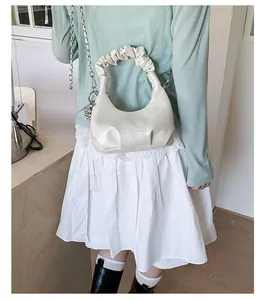 Detail of cream crescent bag with pleated handle and silver chain strap on model