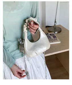 Detail of off-white pleated handbag with scrunchie handle and silver chain strap