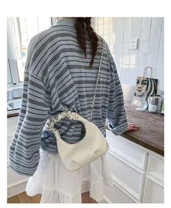 Detailed back view of a creamy white ruched hobo bag with stylish metal chain strap