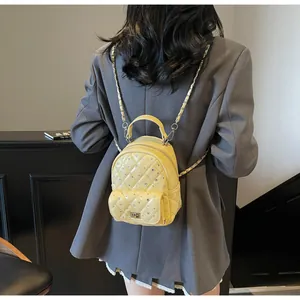 Close-up of a yellow quilted mini backpack with sparkling rhinestones and chain strap