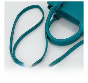 Detail of the litchi texture green leather handbag showing strap and stitching quality