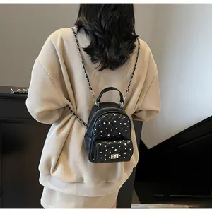Detail of black quilted mini backpack with silver studs and chain shoulder straps