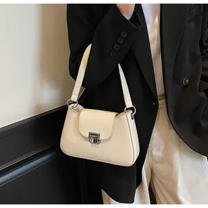 Détail d'un sac sous les bras beige avec texture en cuir plissé et boucle argentée