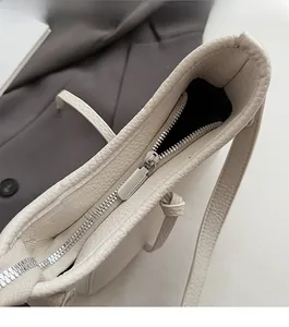 Details des silbernen Reißverschlusses und der Narbenleder-Textur der cremeweißen Tasche