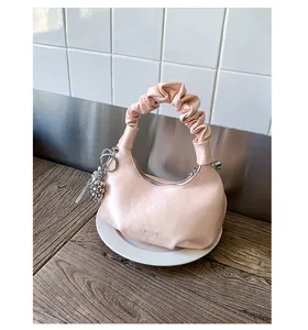 Macro detail of peach pink pleated handle bag with silver zipper and sphere charm
