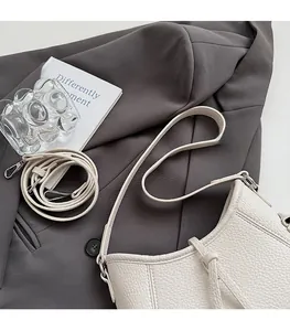 Detail der beigen Handtasche aus Leder mit Litschistruktur und zwei Schultergurten