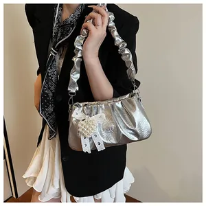 Detailed shot of silver pleated metallic handbag with pearl heart and lace bow charm