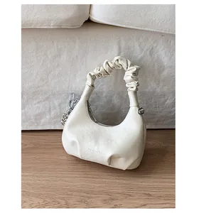 Detail of white pleated handbag with a silver bead chain accessory on a minimalist background
