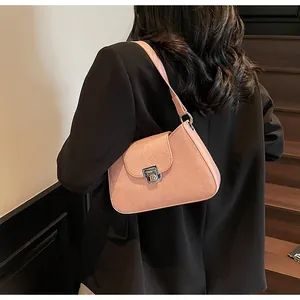 Salmon pink underarm bag with silver twist lock shown on a model in a black suit