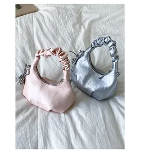 Detail of pink and silver pleated handle handbags with soft faux leather texture