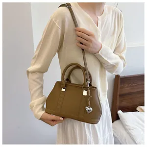 Brown lychee leather crossbody bag with silver heart pendant charm and shoulder strap