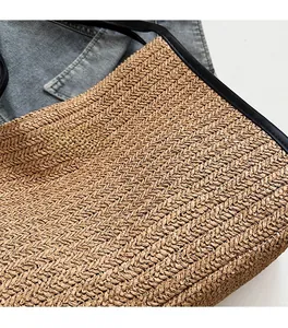 Close-up of hand-woven straw texture and black leather trim detail on a tote bag