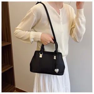 Close-up of black lychee grain leather handbag with silver heart pendant and shoulder strap