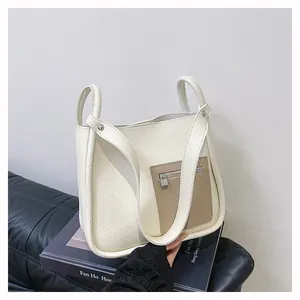 Detail of white litchi pattern tote bag with brown contrast pocket on photography book