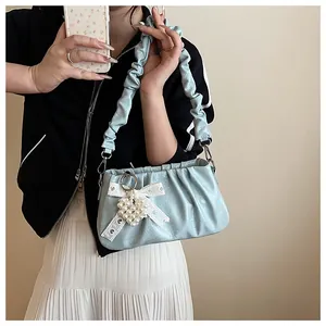 Detail of light blue pleated shoulder bag with lace bow and pearl heart charm accessory